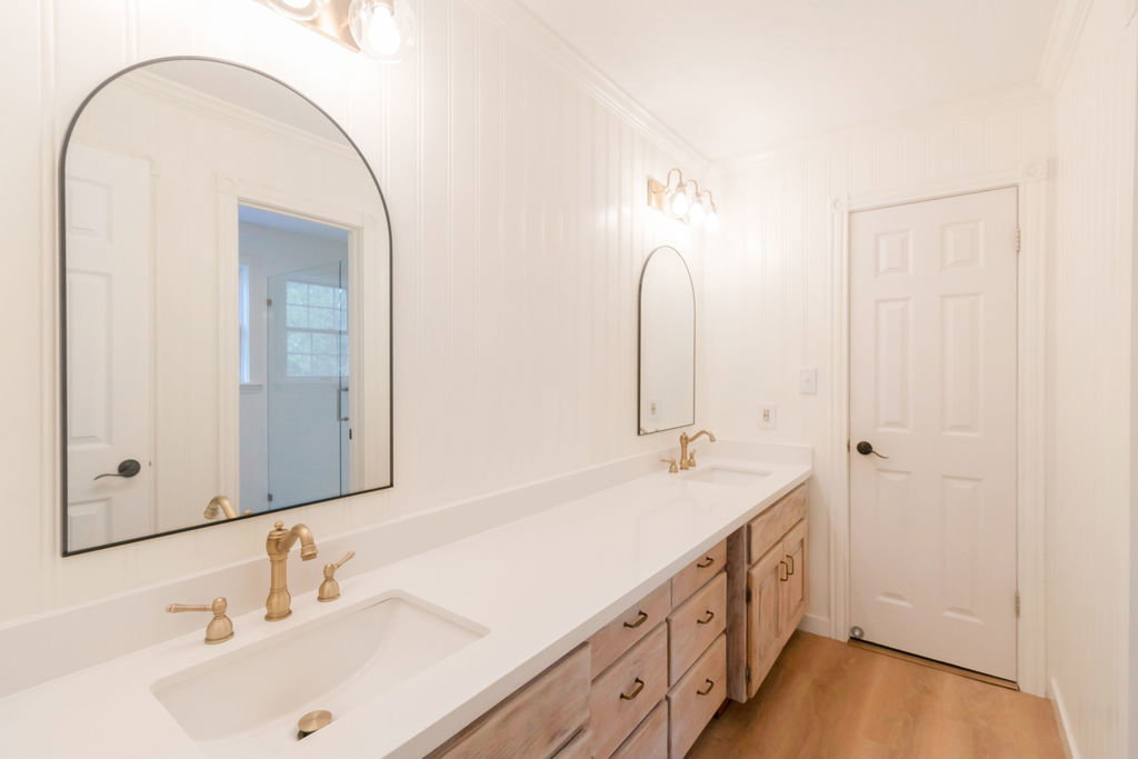 Dual vanity with white countertops, undermount sinks, and brass-finish fixtures