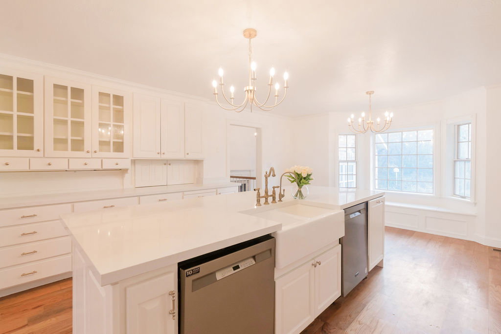 Spacious kitchen featuring an expansive island with a farmhouse sink and integrated dishwasher
