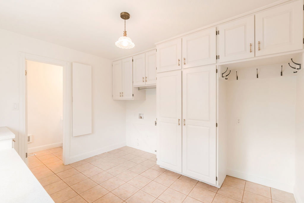 Utility area featuring extensive built-in cabinetry, tiled flooring, and a dedicated laundry appliance hookup