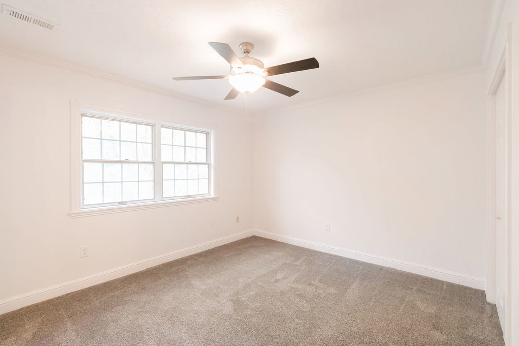 Room featuring neutral paint, gray carpeting, a ceiling fan with integrated lighting, and multiple pane windows