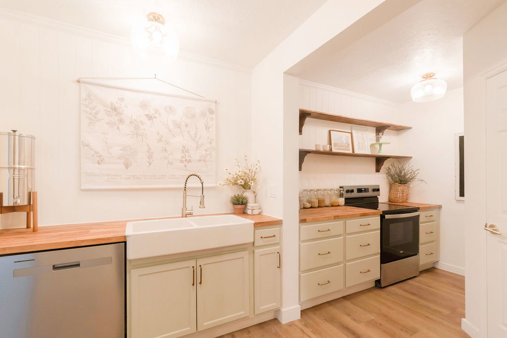 Bright kitchen featuring a double basin farmhouse sink, wood-finish countertops, stainless steel appliances, and open shelving