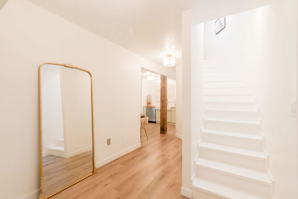 Bright white walls and staircase complemented by wood-finish flooring