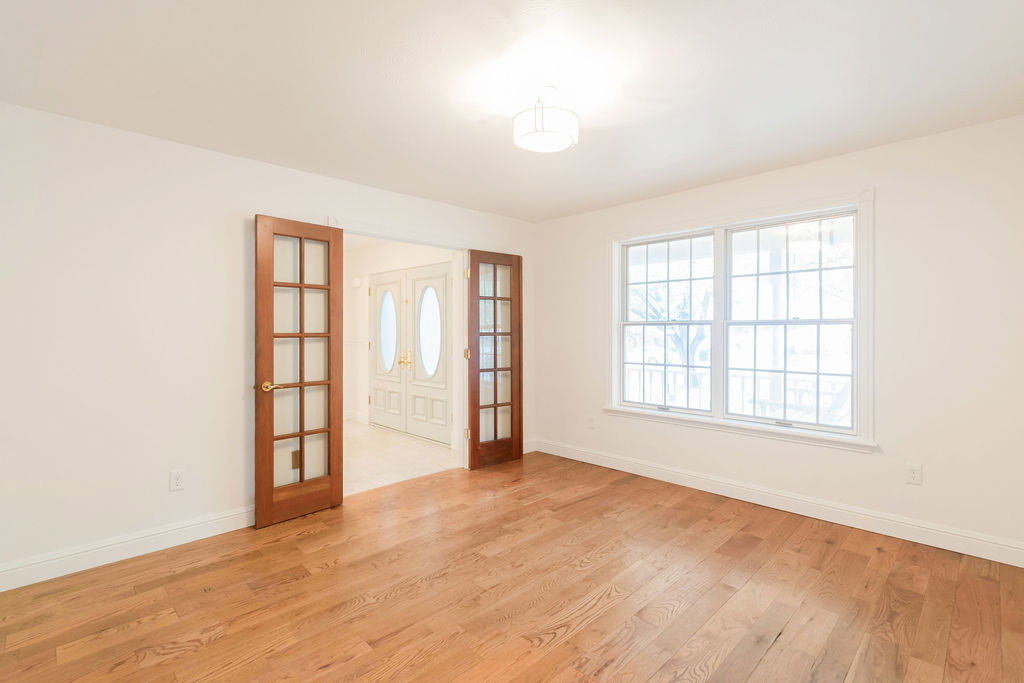 Spacious room featuring wood-finish flooring, white walls, and a ceiling-mounted light fixture