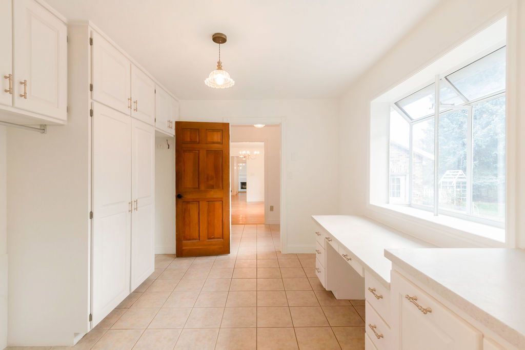 Bright room featuring extensive built-in cabinetry, a built-in desk with drawers, beige tile flooring, and a large bay window