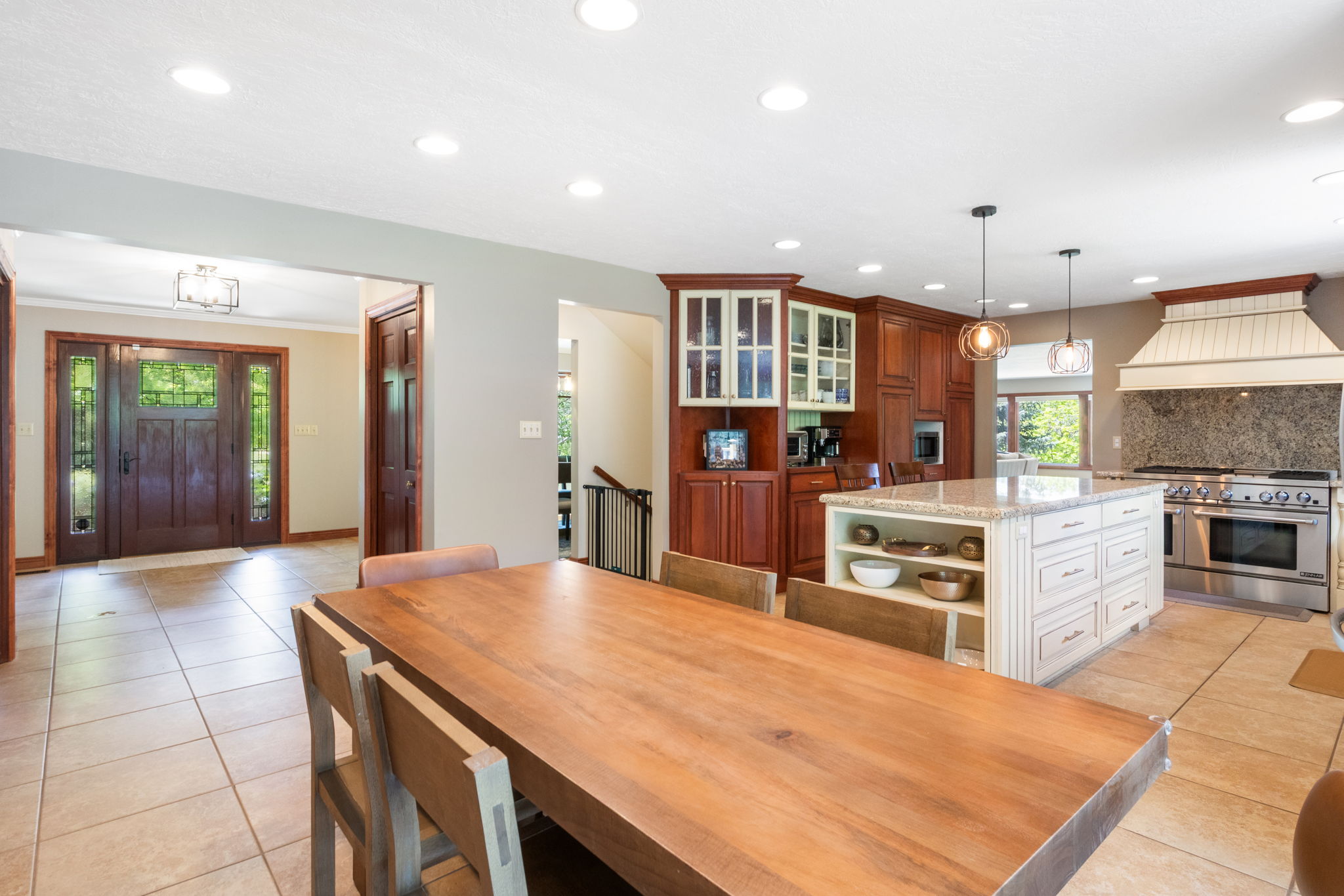Open-concept kitchen and dining area featuring tile flooring, a large central island with integrated storage, and recessed lighting