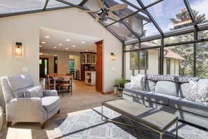 Sunroom featuring a full glass roof, wall-mounted sconces, and tile flooring