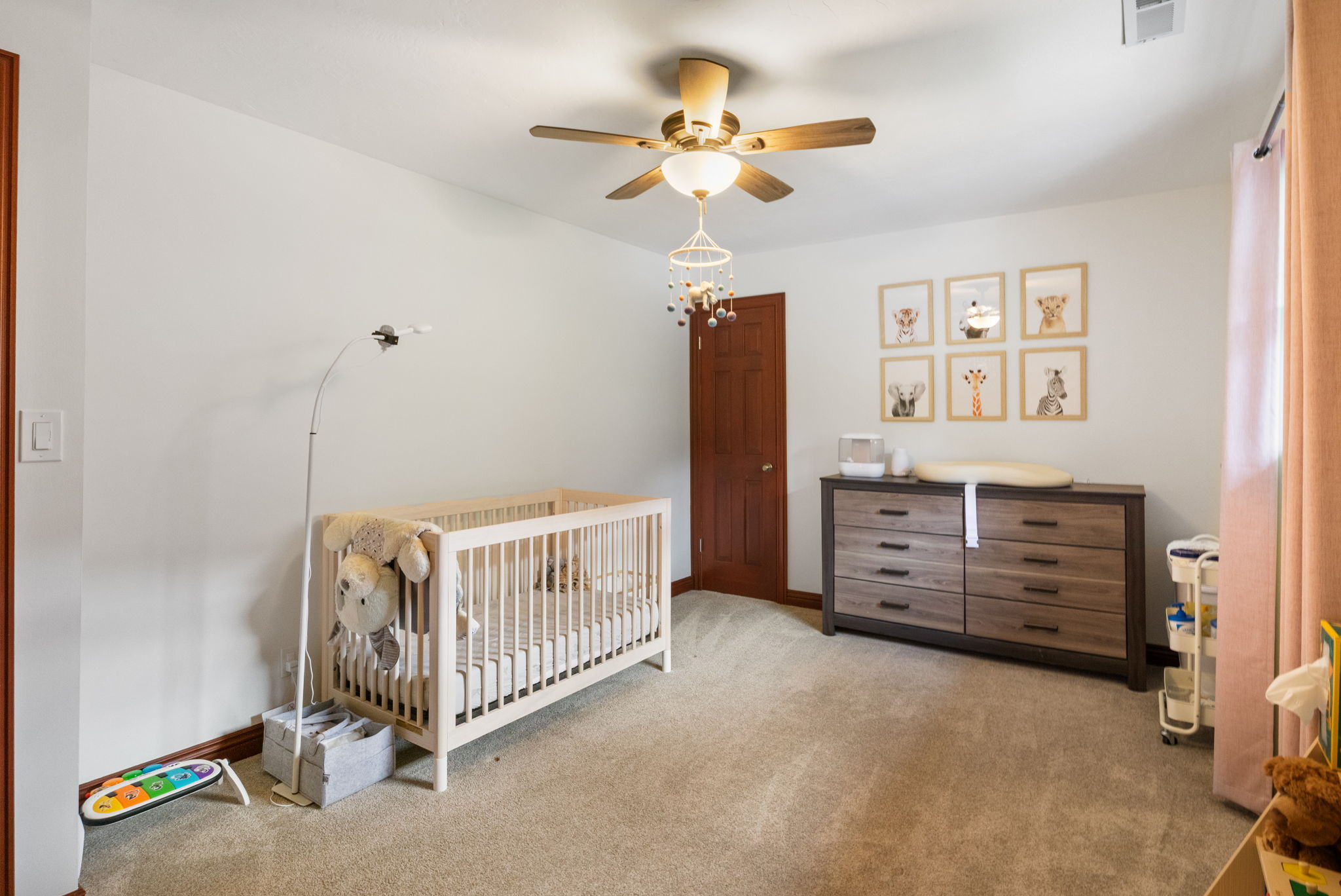 Spacious room featuring neutral carpeting, a ceiling fan with integrated lighting, and a solid wood interior door