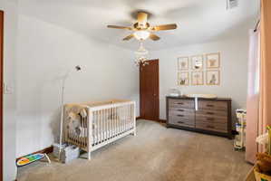 Spacious room featuring neutral carpeting, a ceiling fan with integrated lighting, and a solid wood interior door