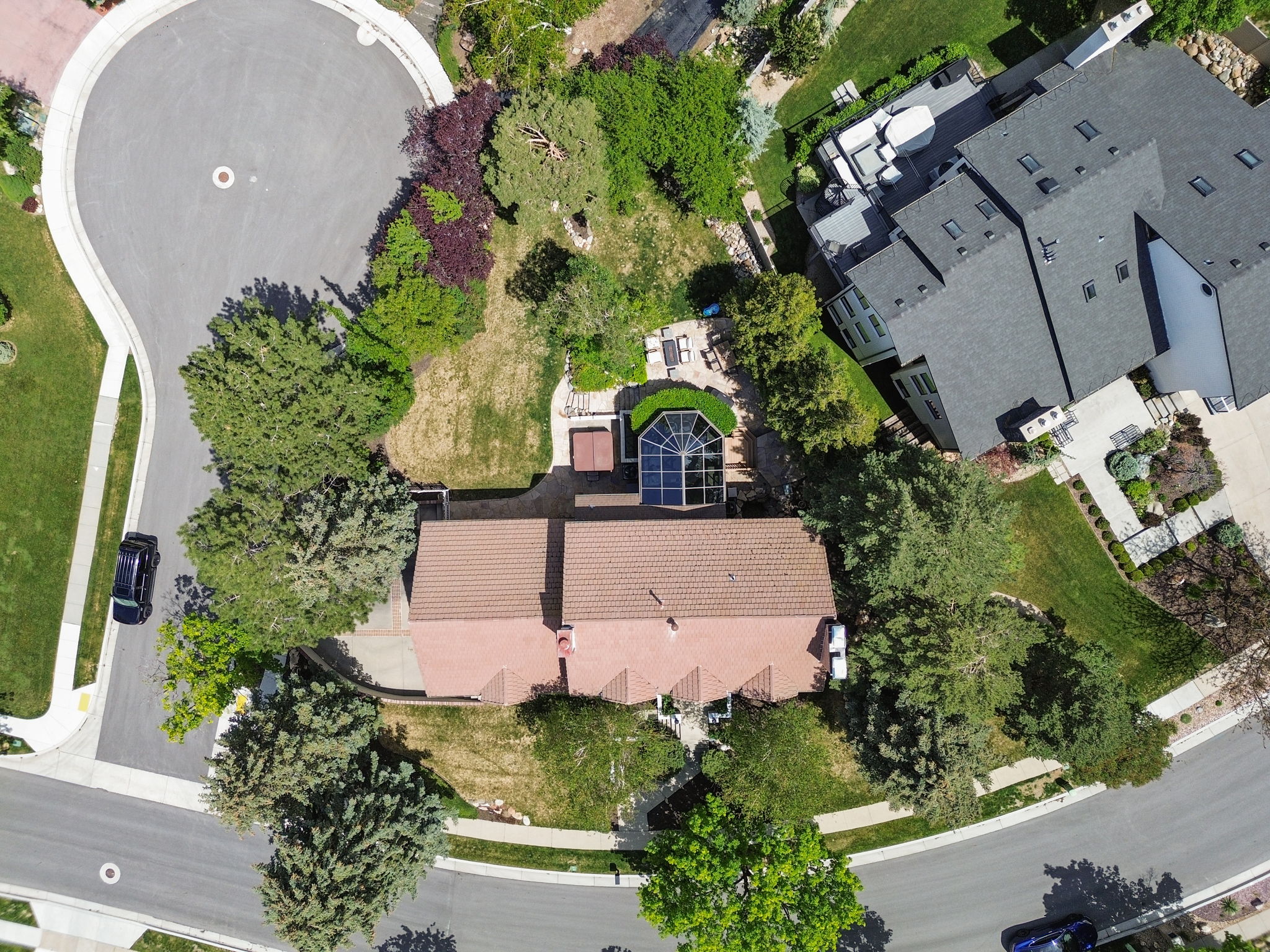 Terracotta-style roofline residence featuring an expansive rear yard, mature landscaping, a sunroom with an arched window design, and an upper-level deck