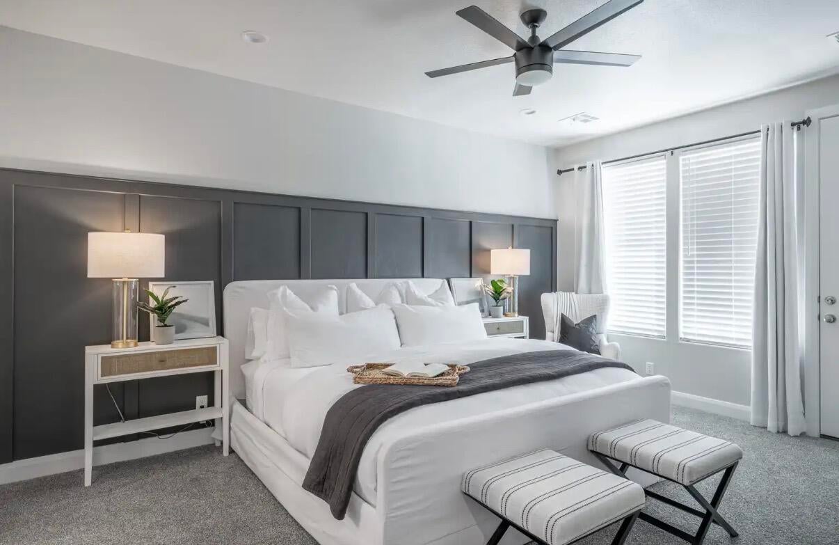 Room featuring a dark paneled accent wall, a ceiling fan with integrated lighting, and carpeted flooring