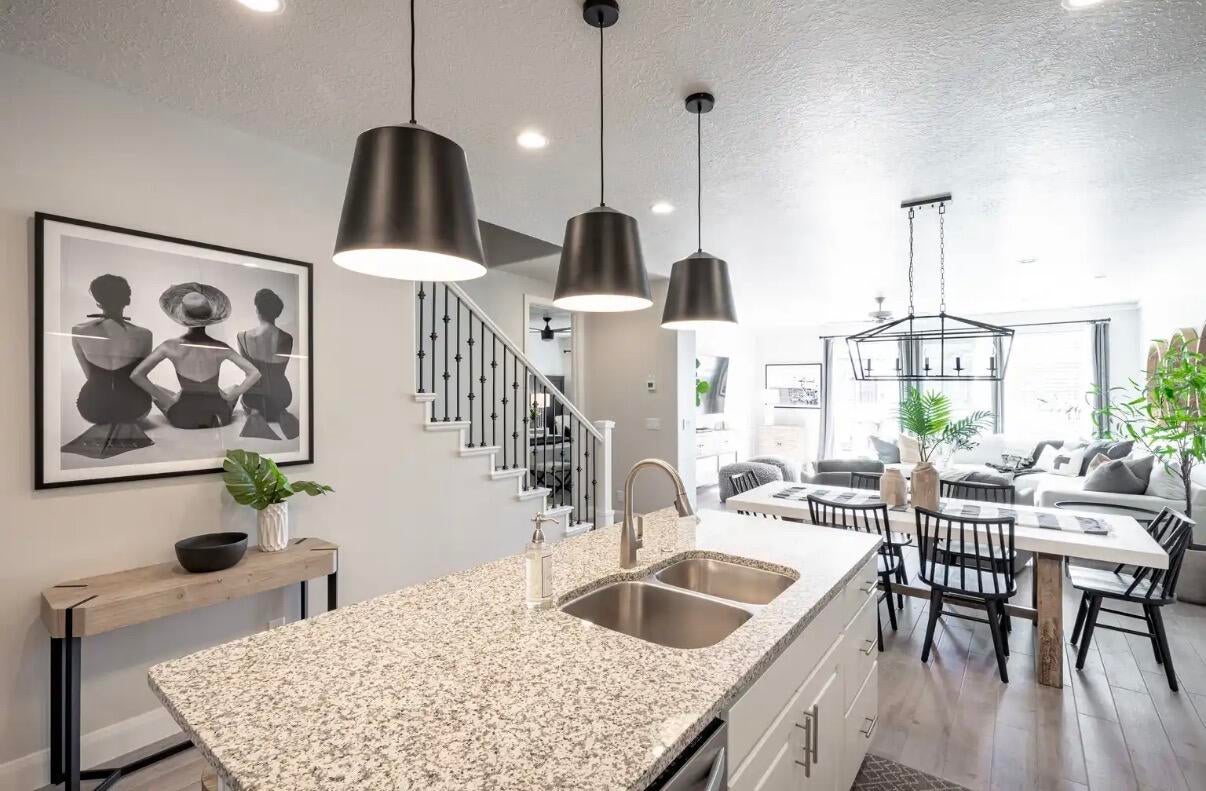 Open-concept living space featuring a kitchen island with a granite countertop and dual stainless steel sinks