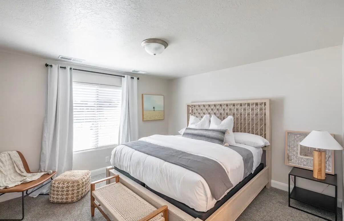 Bedroom featuring a light-toned wood-frame bed with an open geometric headboard