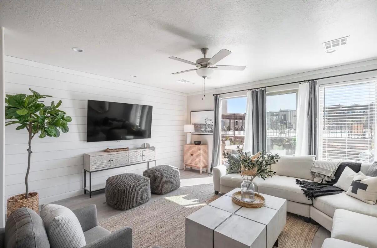 Spacious living area featuring a shiplap accent wall, multiple large windows, recessed lighting, and a ceiling fan