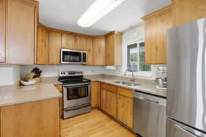 Kitchen featuring wood-finish cabinetry, light-toned countertops, and stainless steel appliances