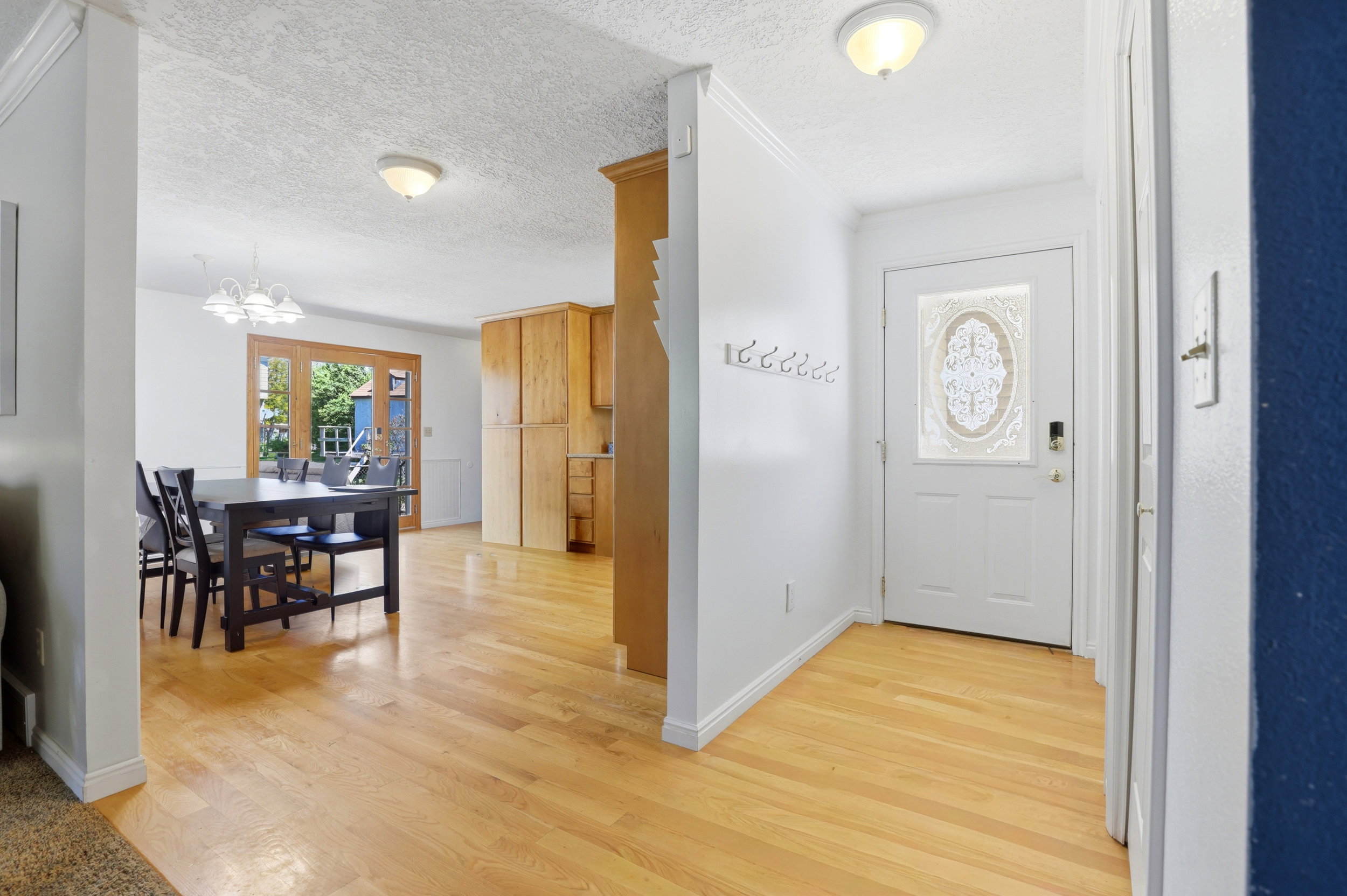 Entryway featuring light wood-finish flooring, a decorative glass-paneled front door, and white walls