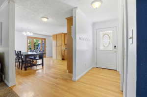 Entryway featuring light wood-finish flooring, a decorative glass-paneled front door, and white walls