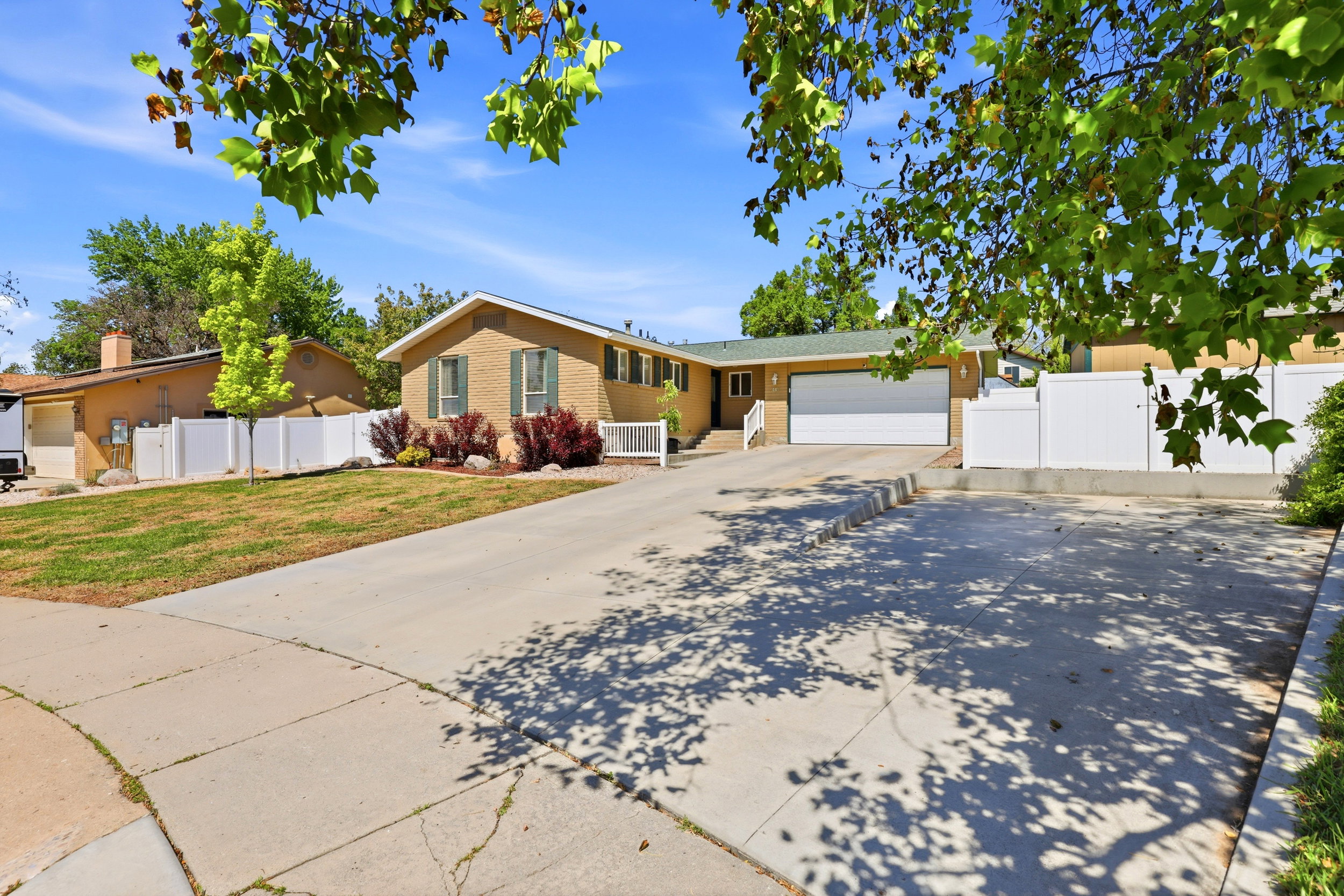 Brick exterior residence with a two-car garage, concrete driveway, and mature landscaping