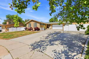 Brick exterior residence with a two-car garage, concrete driveway, and mature landscaping