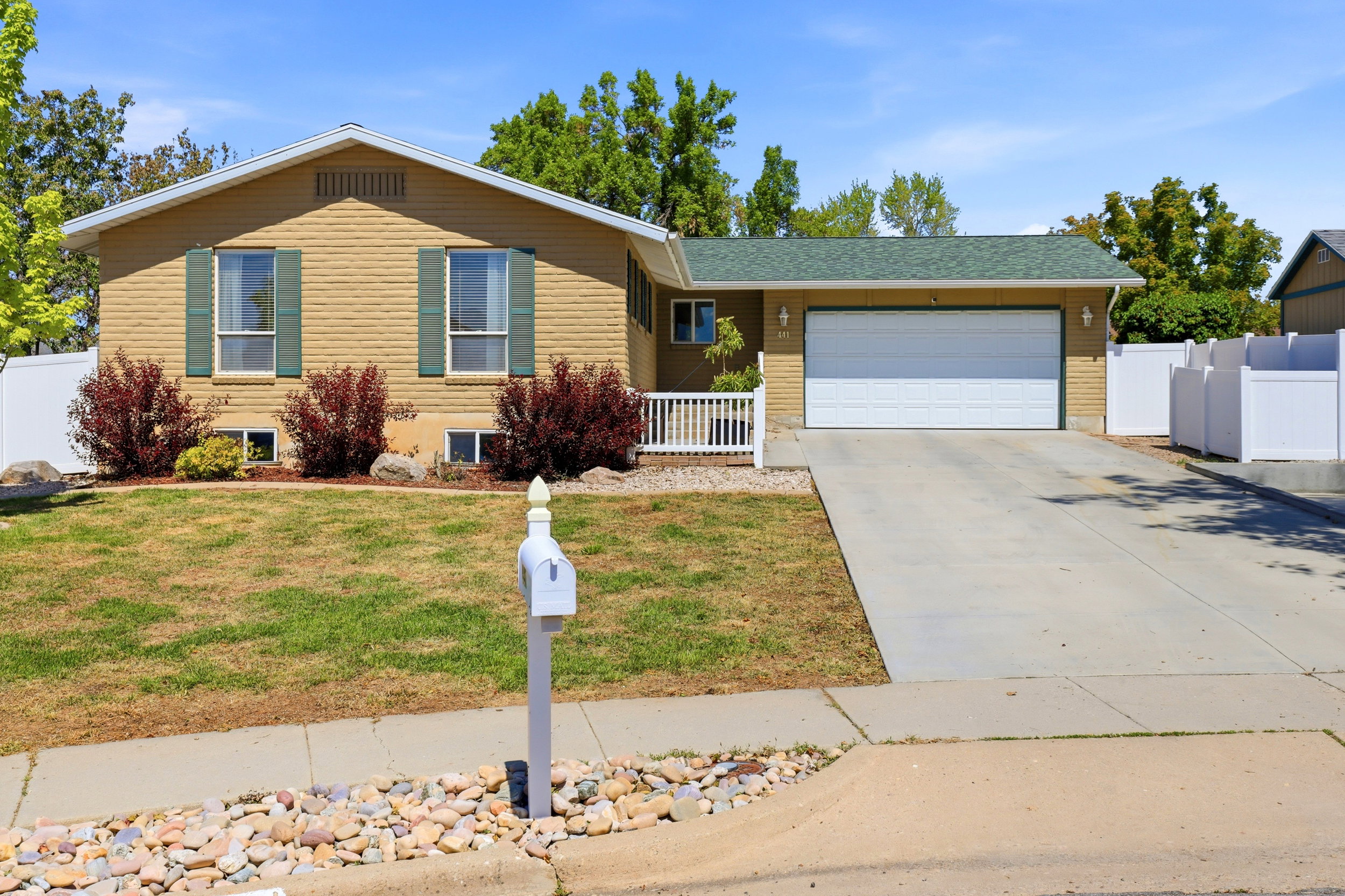 Single-story residence featuring a two-car garage, concrete driveway, and a white picket fence