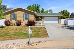 Single-story residence featuring a two-car garage, concrete driveway, and a white picket fence