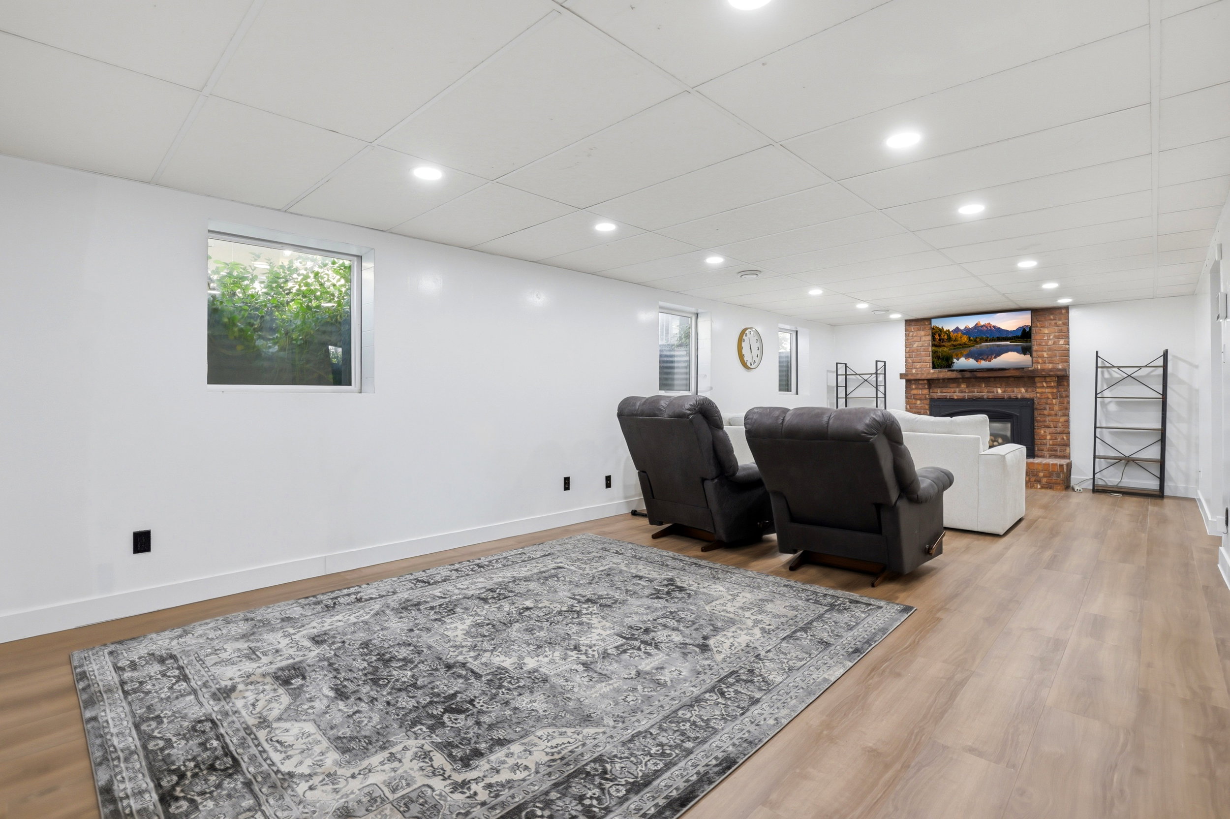 Finished basement featuring wood-finish flooring, recessed lighting, and a red brick fireplace