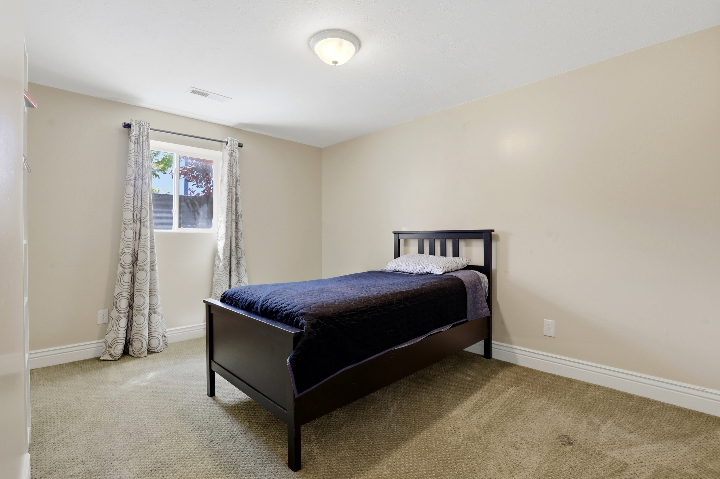 Bright room featuring a window with white trim, a flush-mount ceiling light fixture, neutral-toned walls, white baseboards, and carpeted flooring