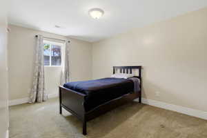Bright room featuring a window with white trim, a flush-mount ceiling light fixture, neutral-toned walls, white baseboards, and carpeted flooring