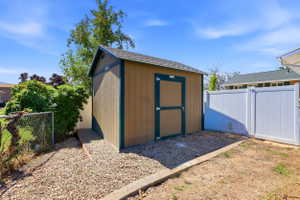 Exterior storage shed featuring a pitched roof, tan siding, and dark trim