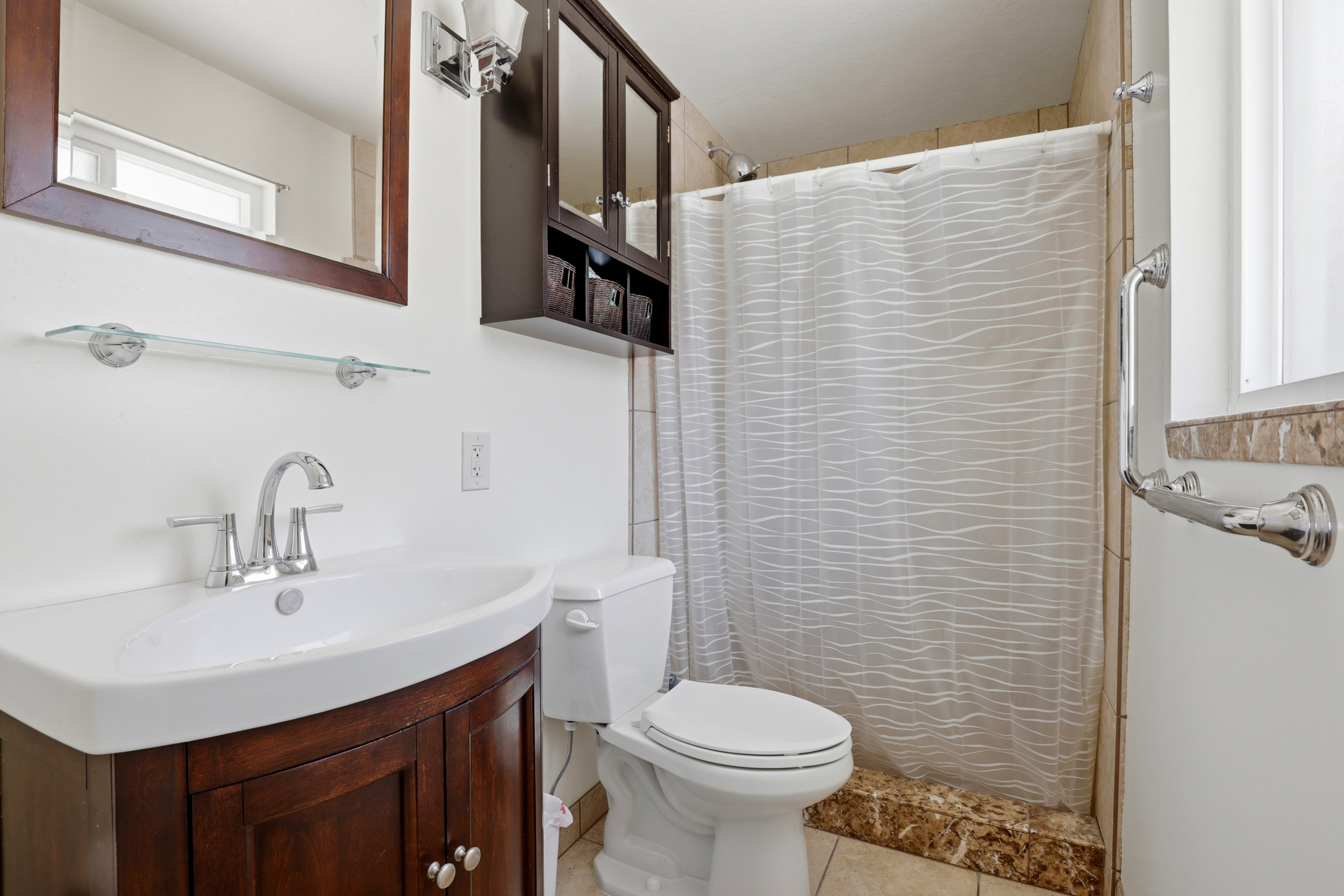 Bathroom vanity with a dark wood-finish cabinet and a white integrated sink, complemented by a chrome faucet