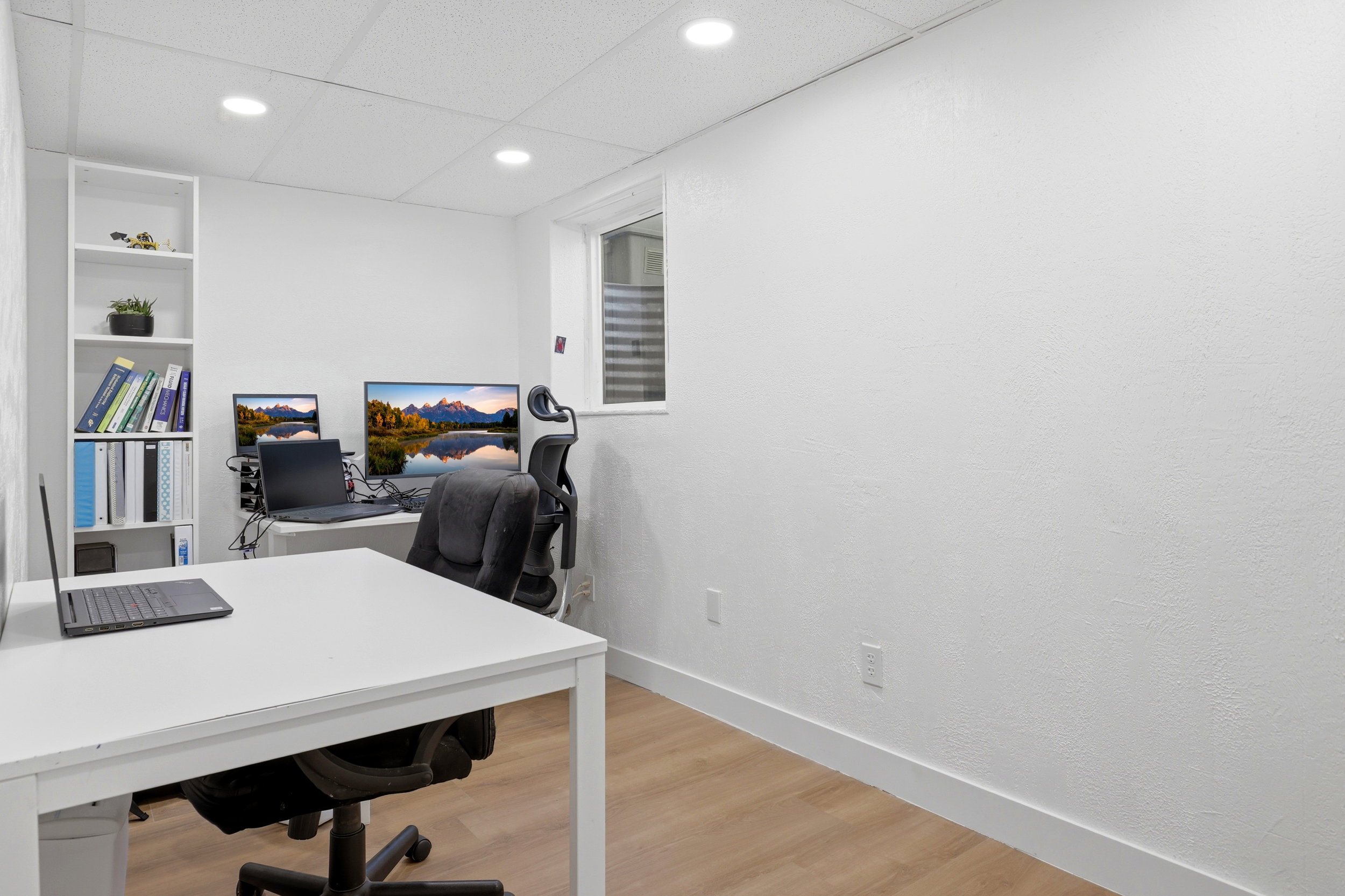 Dedicated room featuring wood-finish flooring, recessed lighting, a built-in shelving unit, and a window with horizontal blinds