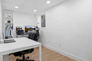 Dedicated room featuring wood-finish flooring, recessed lighting, a built-in shelving unit, and a window with horizontal blinds
