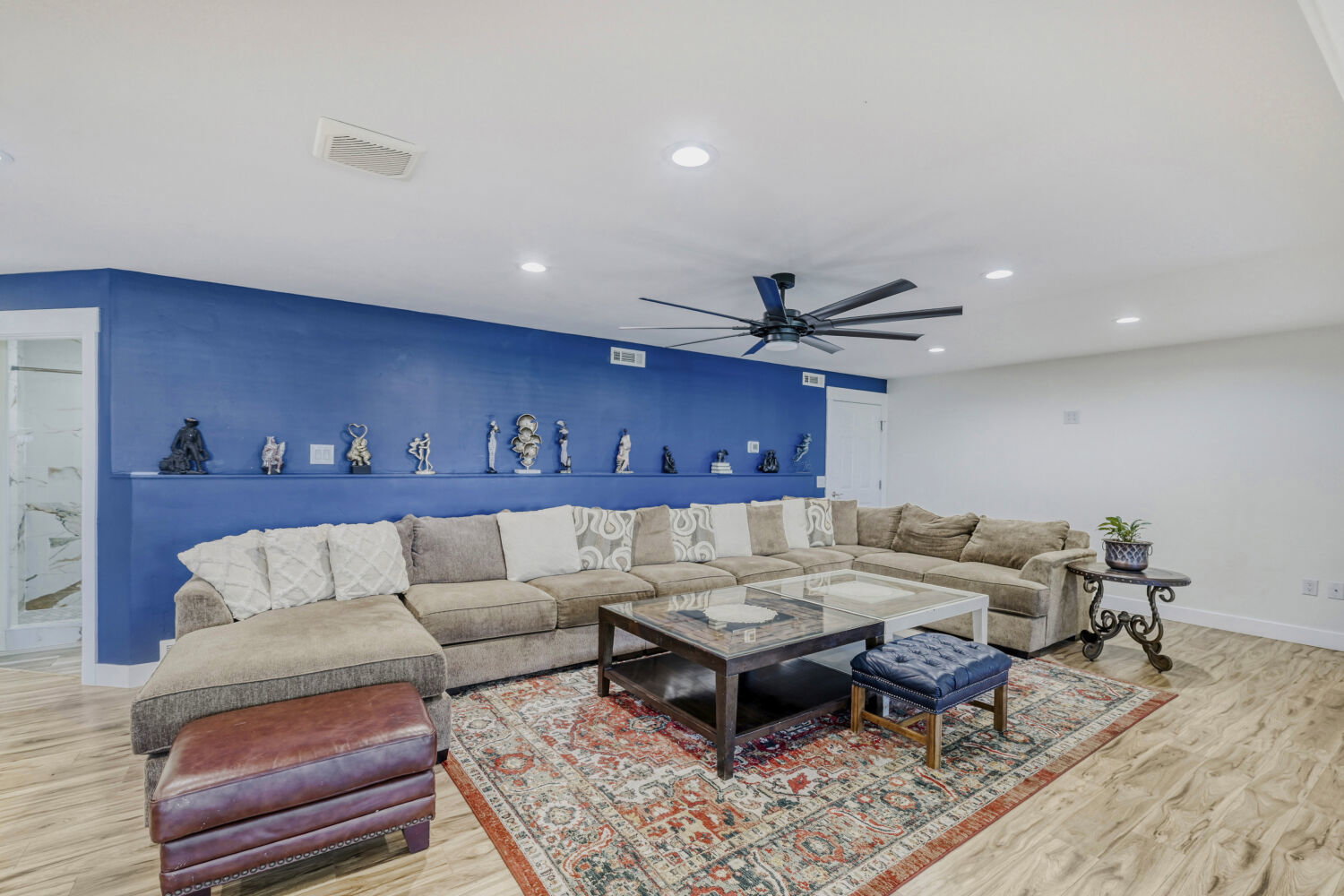 Spacious common area with a built-in display shelf, recessed lighting, and wood-finish flooring, extra large ceiling fan