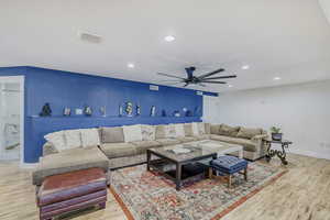Spacious common area with a built-in display shelf, recessed lighting, and wood-finish flooring, extra large ceiling fan