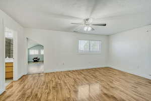 Spacious room featuring wood-finish flooring, a ceiling fan, and a window with blinds
