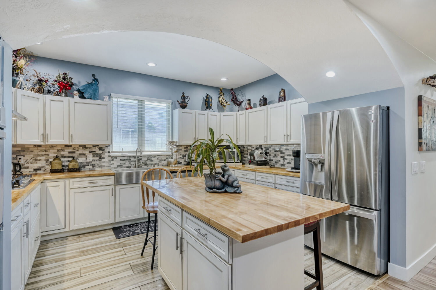 Kitchen featuring an arched entryway, white cabinetry, wood-finish countertops.
