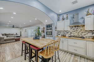 Contemporary kitchen with white cabinetry, wood-finish countertops, a mosaic tile backsplash, and stainless steel appliances