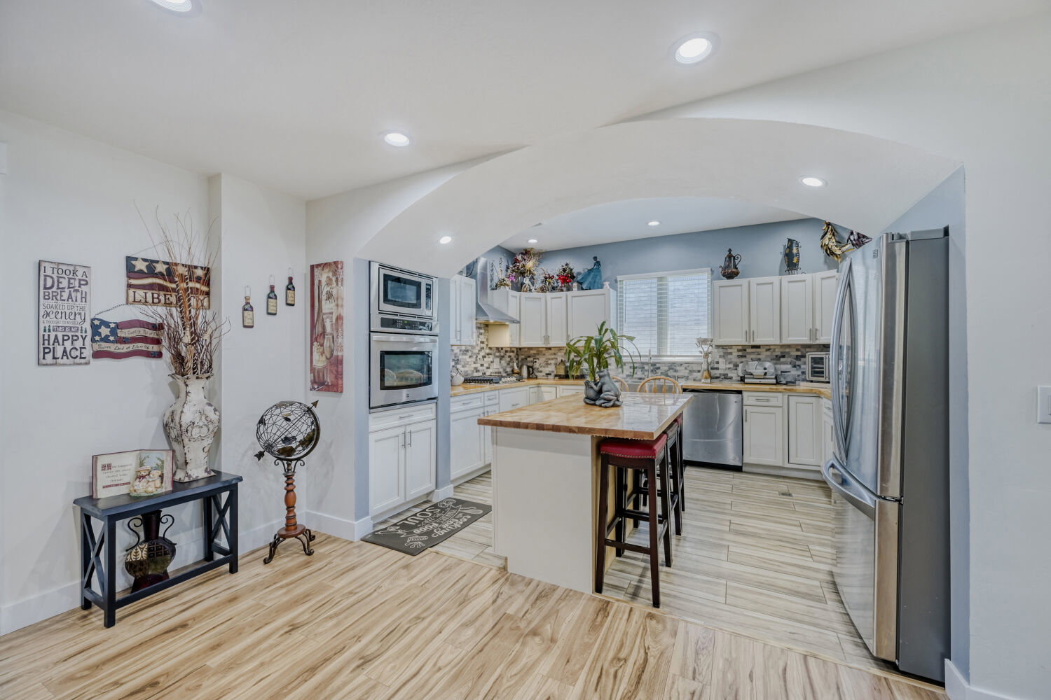 Kitchen featuring a central island with countertop, stainless steel appliances, light-toned cabinetry, and wood-finish flooring