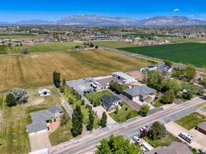 Expansive property featuring a residence with an attached garage, a large detached workshop, substantial paved parking areas, and surrounding green fields