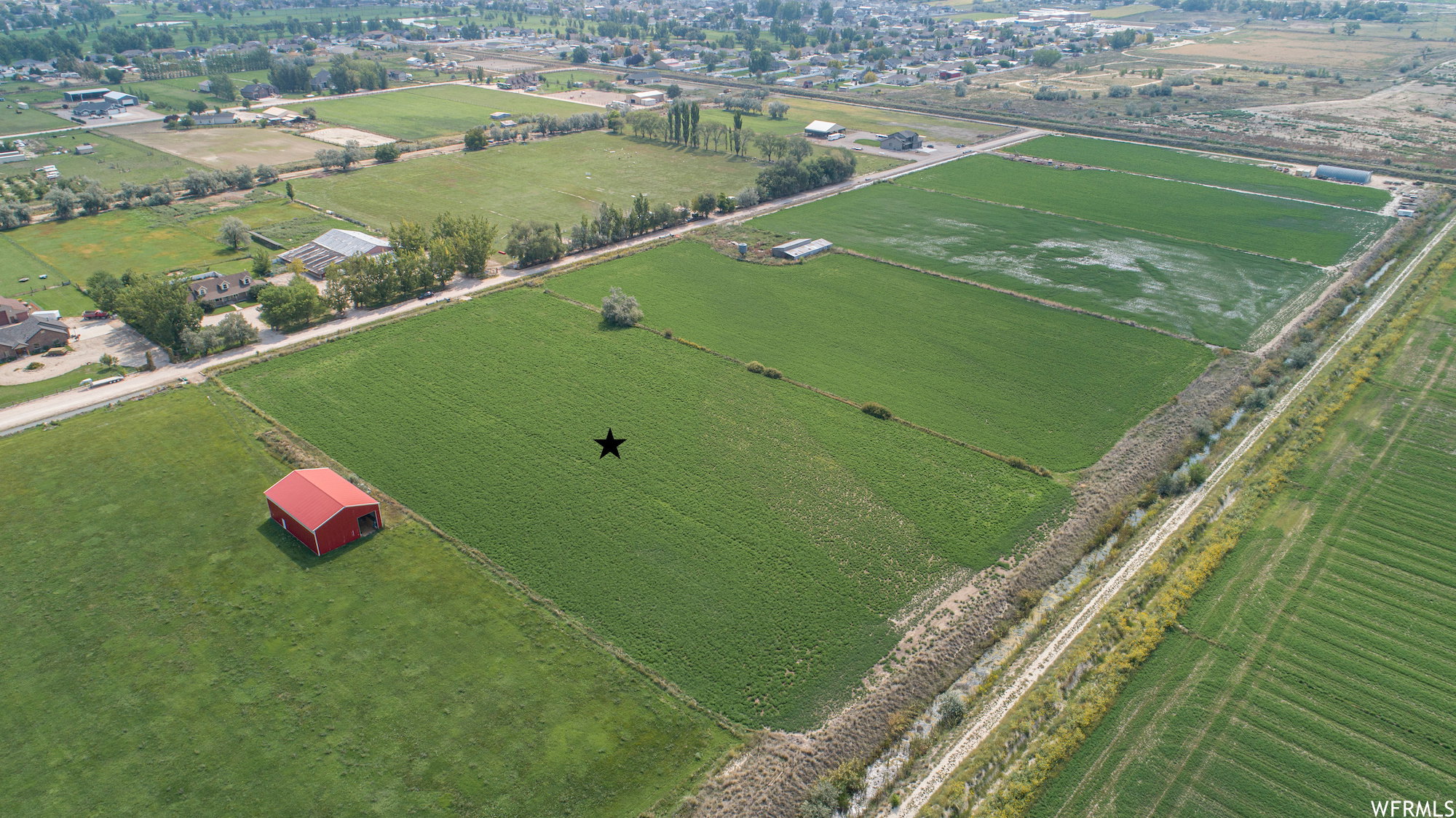 Expansive green fields with a red barn structure