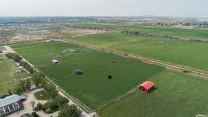Expansive agricultural land featuring a red barn, a smaller outbuilding, and established trees