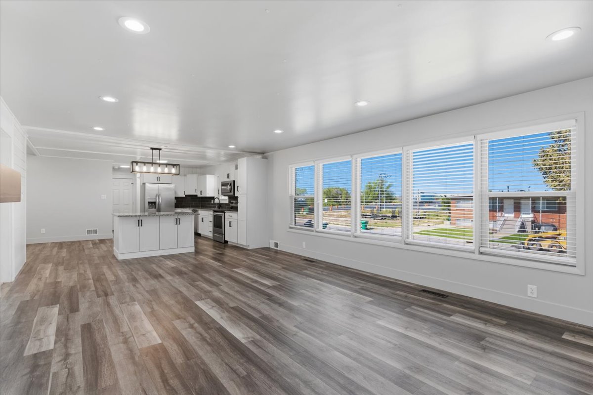 Open-concept living space featuring vinyl flooring, recessed lighting, and kitchen with white cabinetry