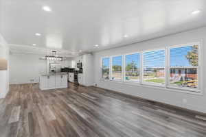 Open-concept living space featuring vinyl flooring, recessed lighting, and kitchen with white cabinetry