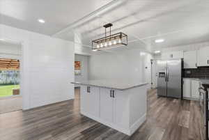 Large kitchen island with a granite countertops, white cabinetry, and matte black hardware