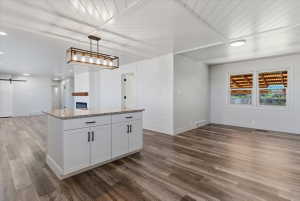 Central kitchen island featuring a granite countertop, white cabinetry, and matte black hardware
