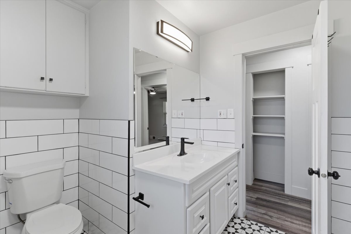 Full bathroom featuring subway tile, white vanity with integrated sink, matte black fixtures, and a geometric tile floor pattern