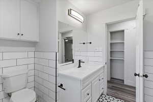 Full bathroom featuring subway tile, white vanity with integrated sink, matte black fixtures, and a geometric tile floor pattern