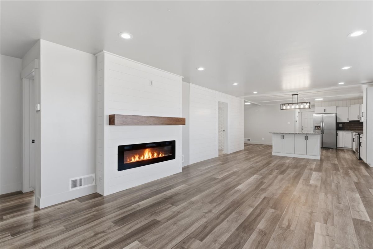 Spacious living area featuring vinyl flooring and a modern electric fireplace with a wood mantle