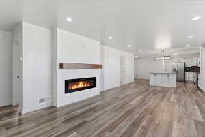 Spacious living area featuring vinyl flooring and a modern electric fireplace with a wood mantle