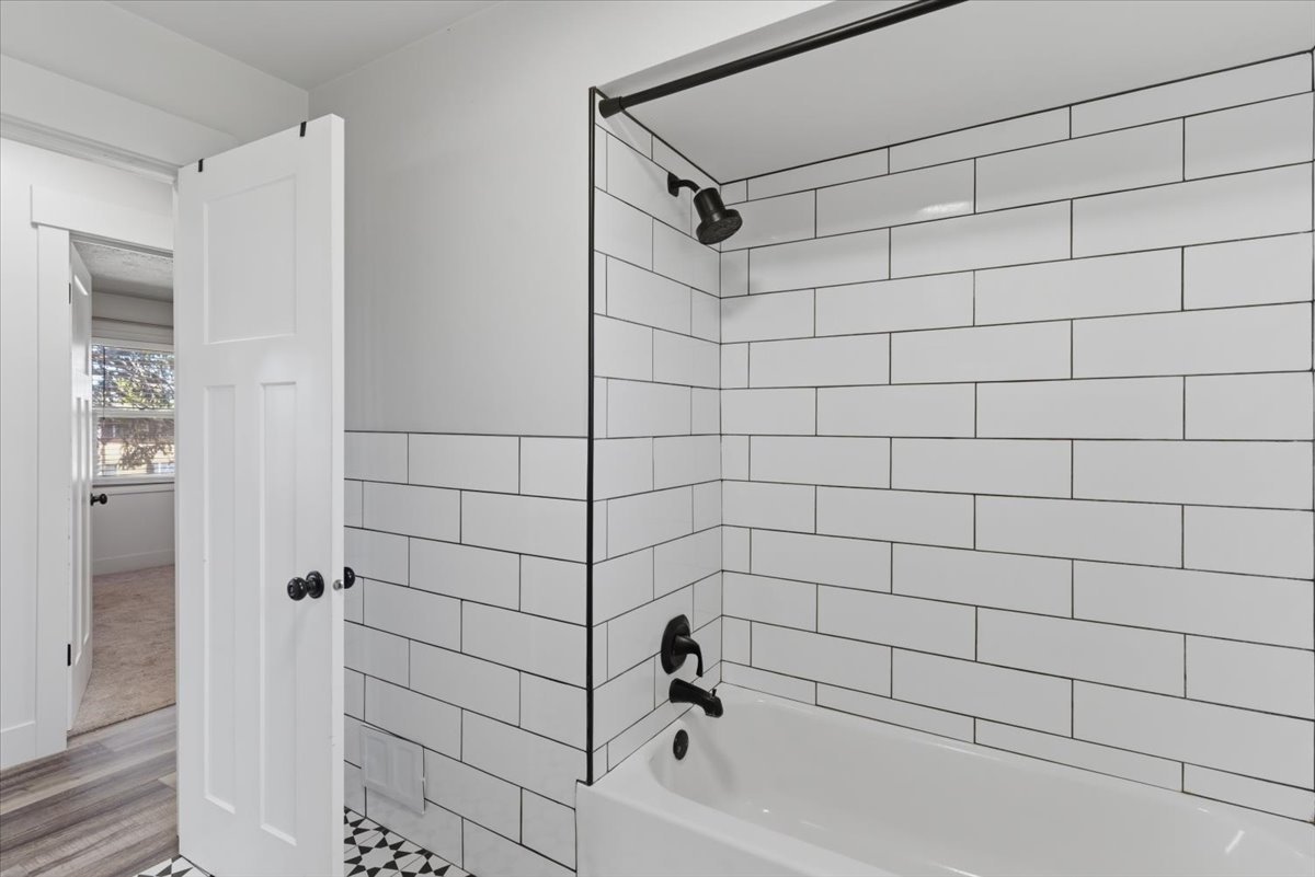 Full bathroom featuring a white subway tile shower surround, matte black shower fixtures, and a white tub