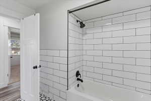 Full bathroom featuring a white subway tile shower surround, matte black shower fixtures, and a white tub